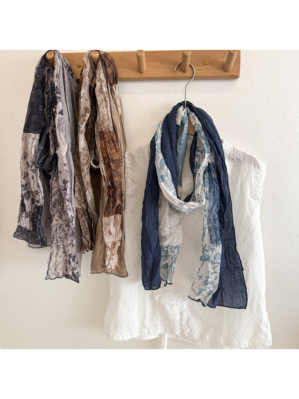 Gray, Khaki, and Navy floral patchwork scarves hanging beside a white top.