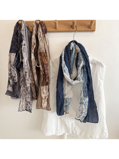 Gray, Khaki, and Navy floral patchwork scarves hanging beside a white top.