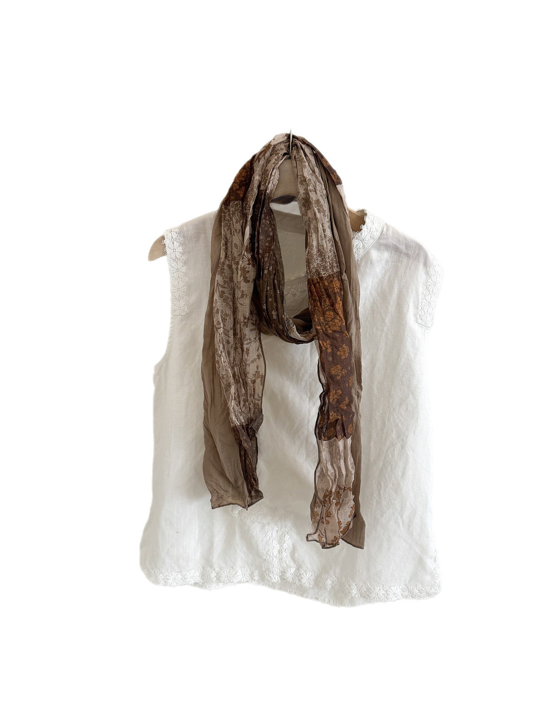 Khaki floral patchwork scarf draped in a long loop over a white top.