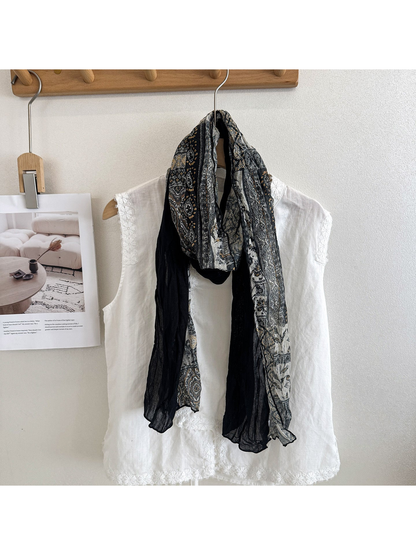 Black Gray scarf with ornamental printed and solid black sections, looped over a white top.