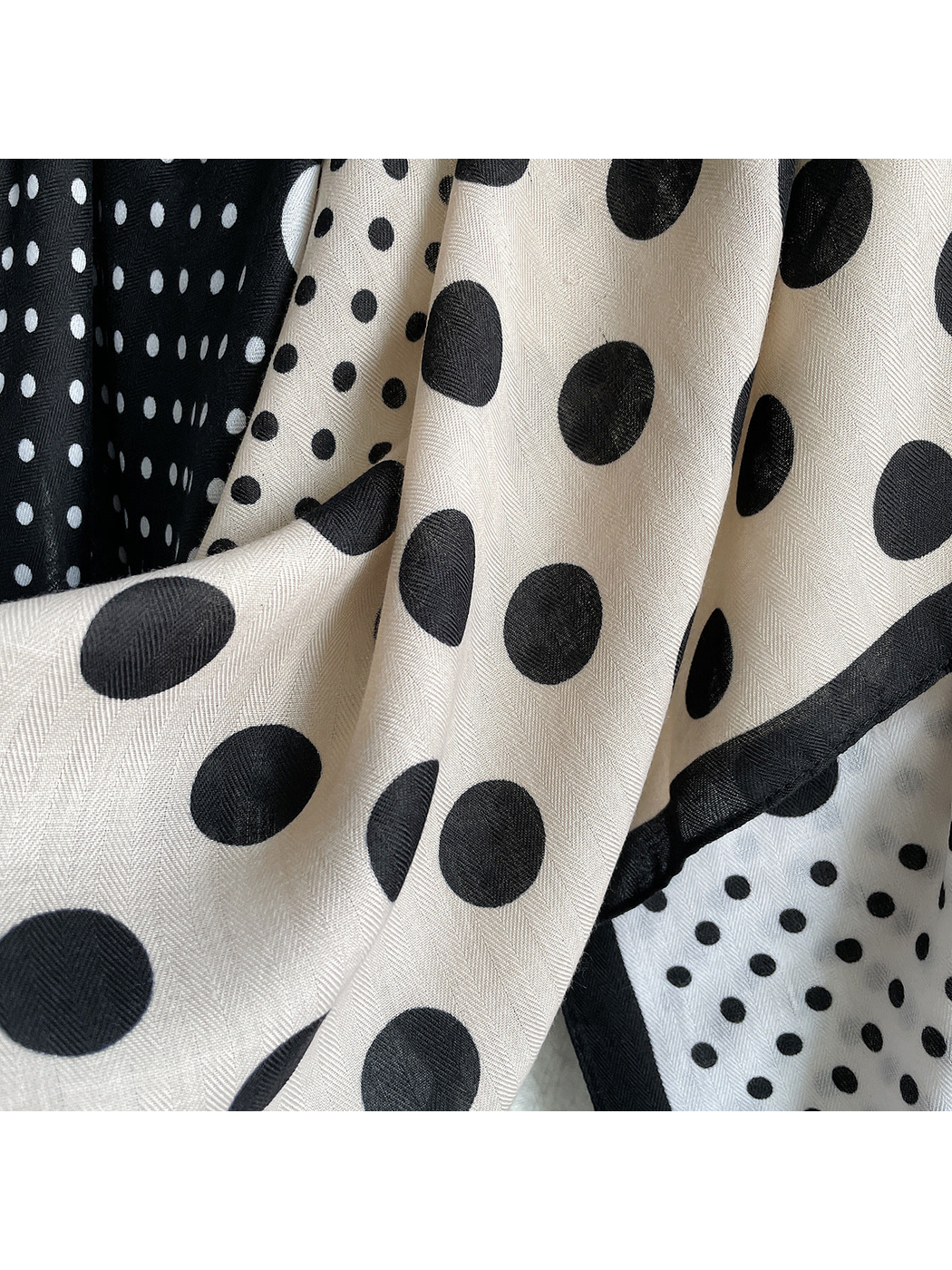 Close-up of contrasting polka dots, fine herringbone texture, and bordered scarf edges.