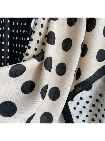 Close-up of contrasting polka dots, fine herringbone texture, and bordered scarf edges.