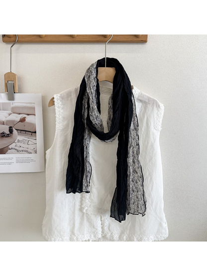 Black Gray scarf with solid and paisley sections looped over a white top.