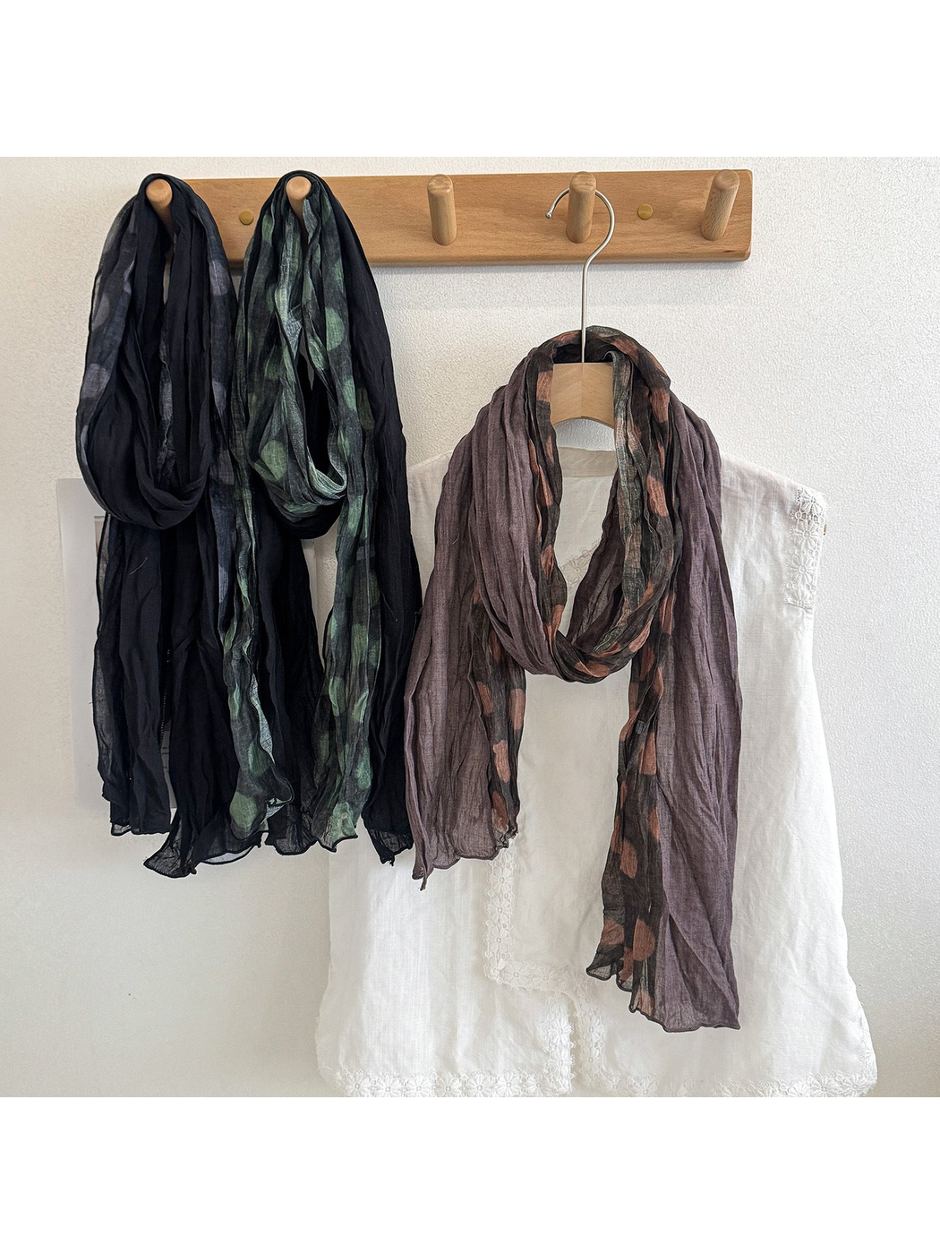 Black, Green and Coffee polka dot scarves hanging in loose loops beside a white blouse.