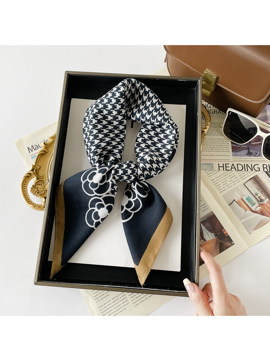 Navy scarf in a knotted loop with white houndstooth, floral motifs and a contrasting brown border.