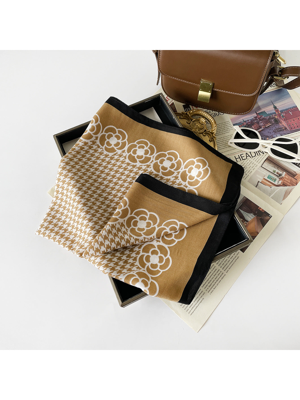 Camel scarf folded to reveal white floral motifs, houndstooth pattern and black edging.