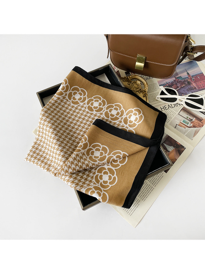 Camel scarf folded to reveal white floral motifs, houndstooth pattern and black edging.