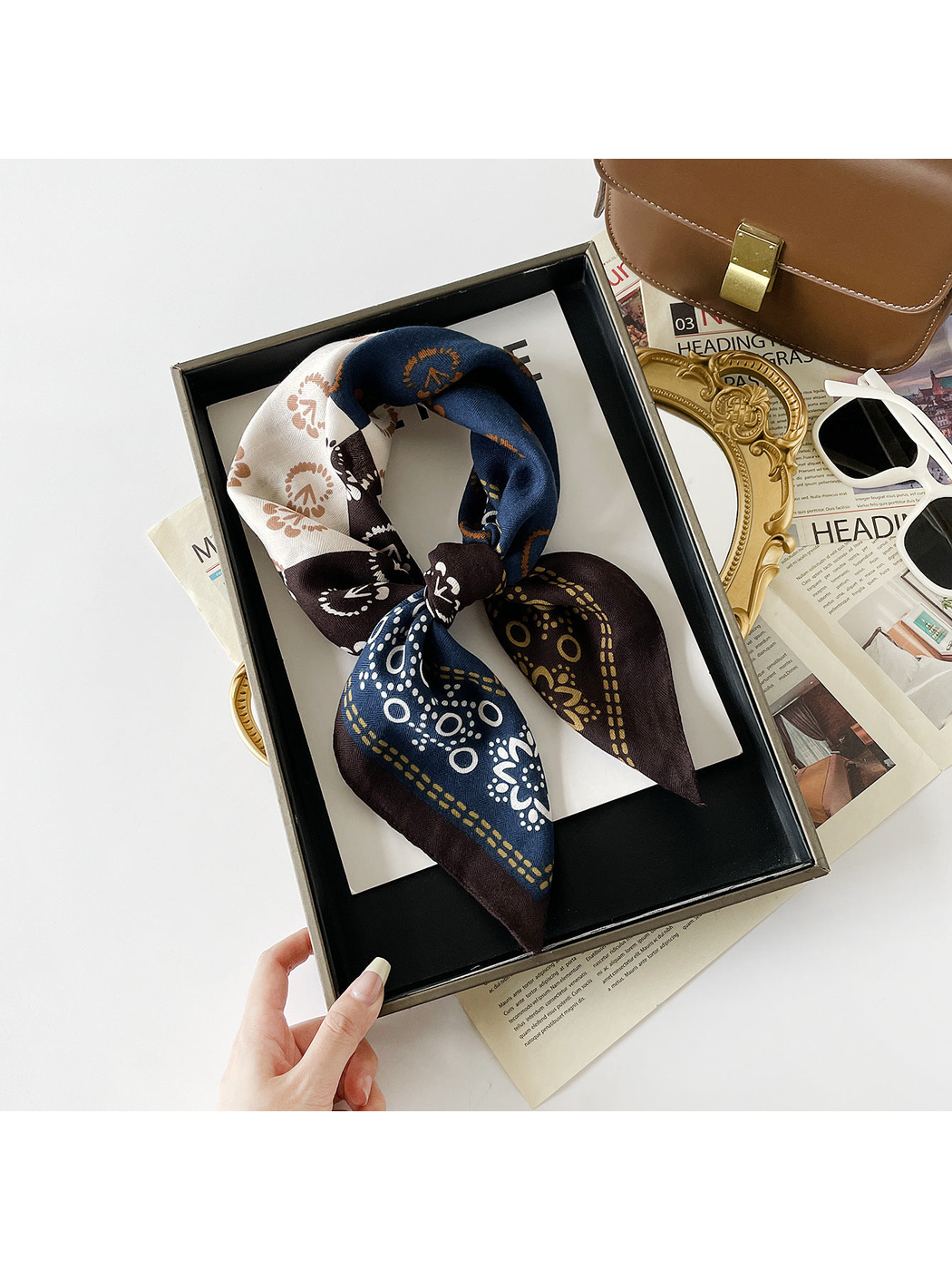 Navy Orange patterned scarf tied into a loop with two pointed ends in a rectangular tray.