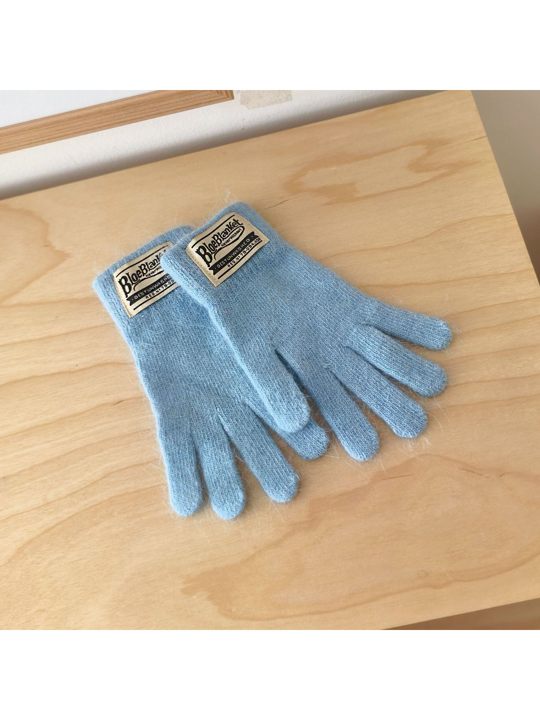 Light Blue knit gloves with contrasting rectangular cuff labels.