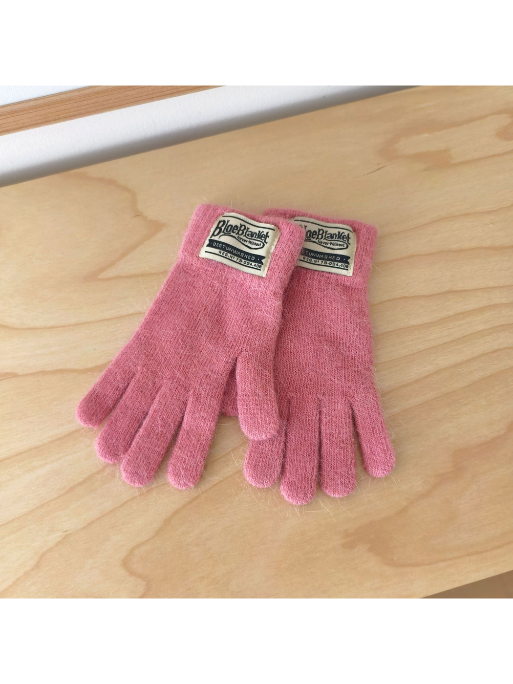 Pink knit gloves with contrasting rectangular cuff labels.