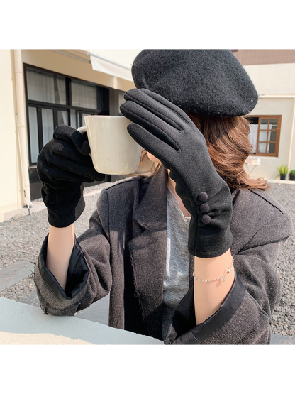 Black gloves with three button accents worn while holding a mug outdoors.