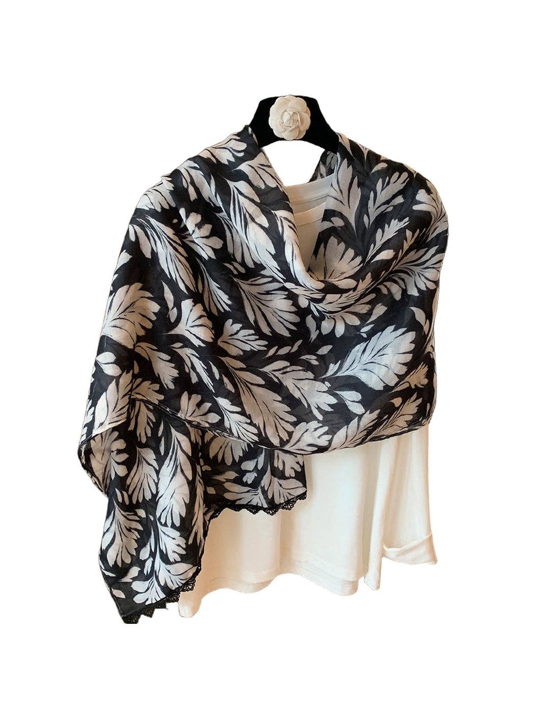 Multicolor botanical leaf-print scarf draped on a hanger, with a lace-trimmed edge visible