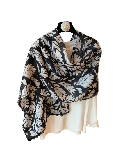Multicolor botanical leaf-print scarf draped on a hanger, with a lace-trimmed edge visible