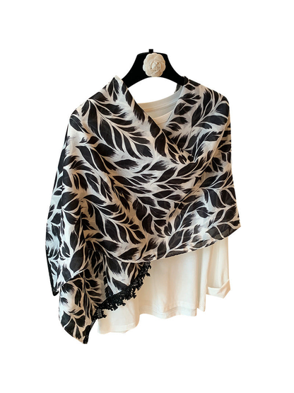 Black-and-white rectangular scarf with a leaf pattern and black lace trim, draped front view