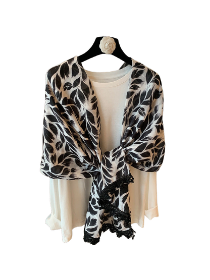 Black-and-white rectangular scarf with a leaf pattern and black lace trim, looped front view