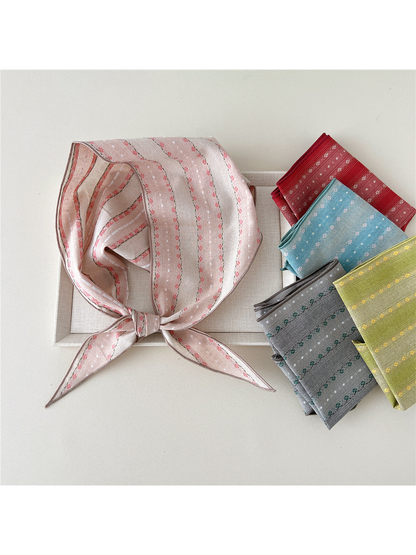 Triangle scarves in multiple floral colorways arranged around a framed display