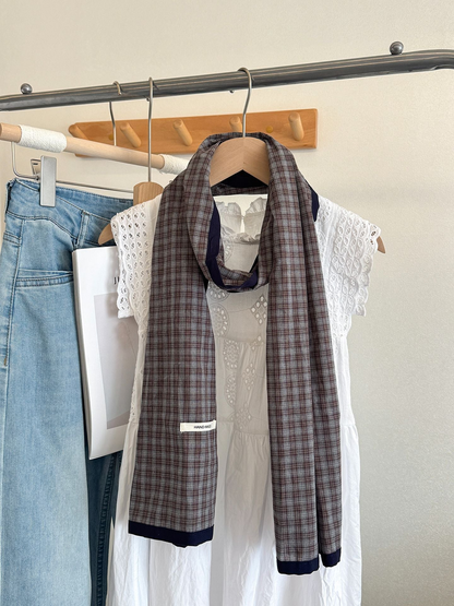 Coffee Fine plaid scarf with navy edging, draped on a hanger