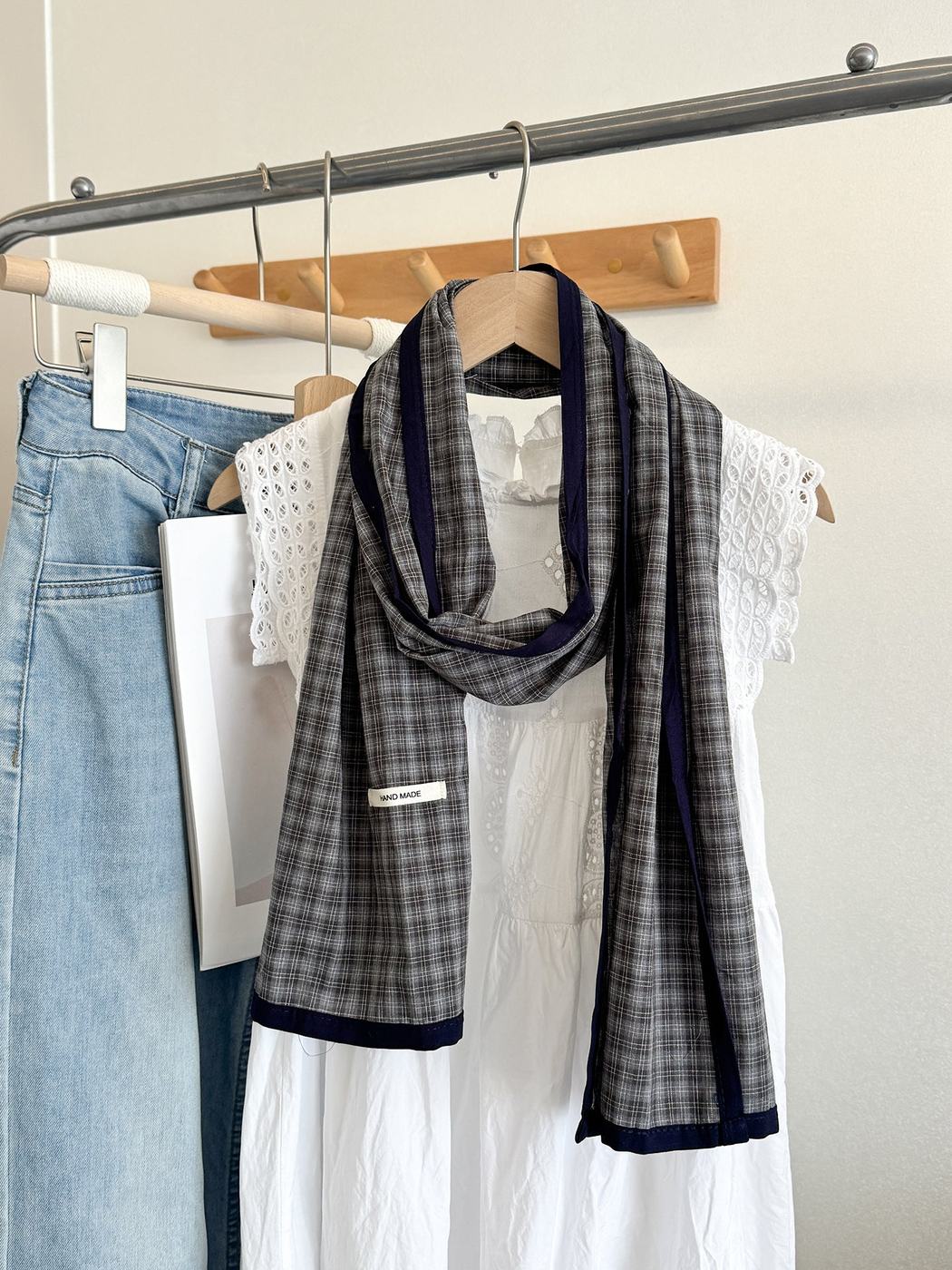 Gray Fine plaid scarf with navy edging, draped on a hanger