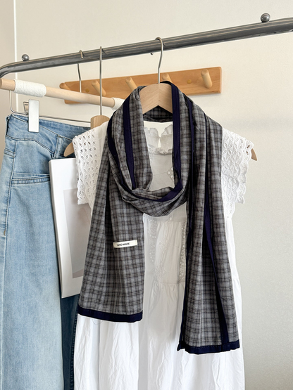Gray Fine plaid scarf with navy edging, draped on a hanger