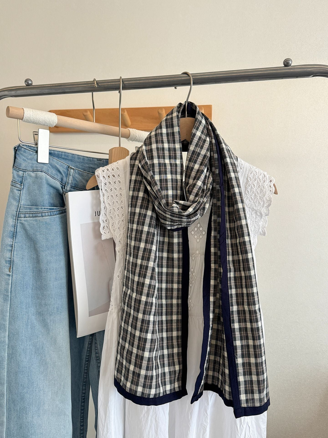 Ivory Large plaid scarf with navy edging, draped on a hanger