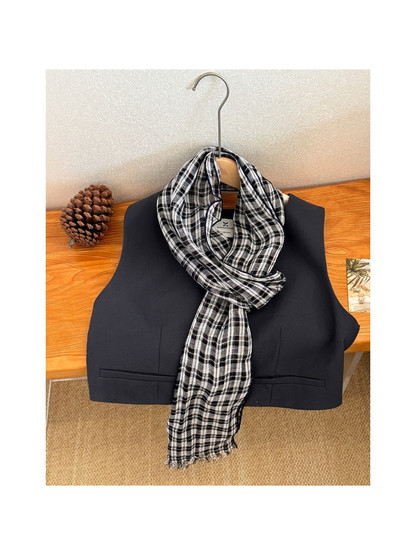 Plaid scarf draped over a black vest, full view