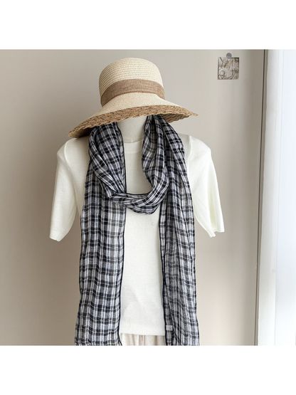 Plaid scarf looped around a mannequin's neck beneath a wide-brim hat