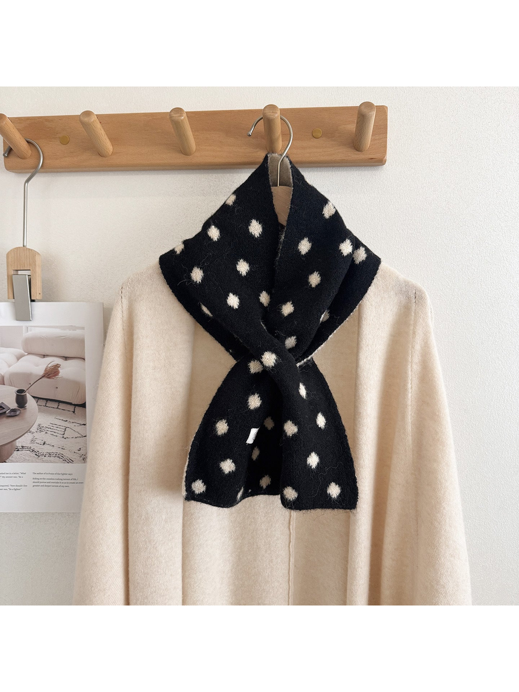 Black polka-dot scarf styled around a cream sweater