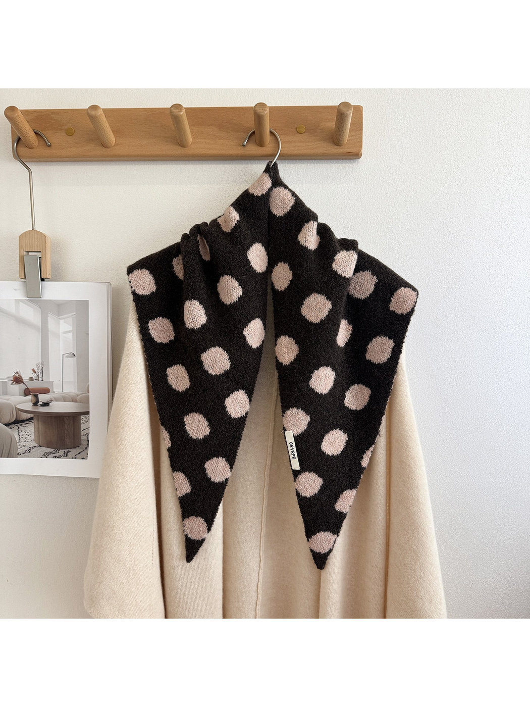 Dark brown and blush polka-dot triangle scarf draped on a cream cardigan
