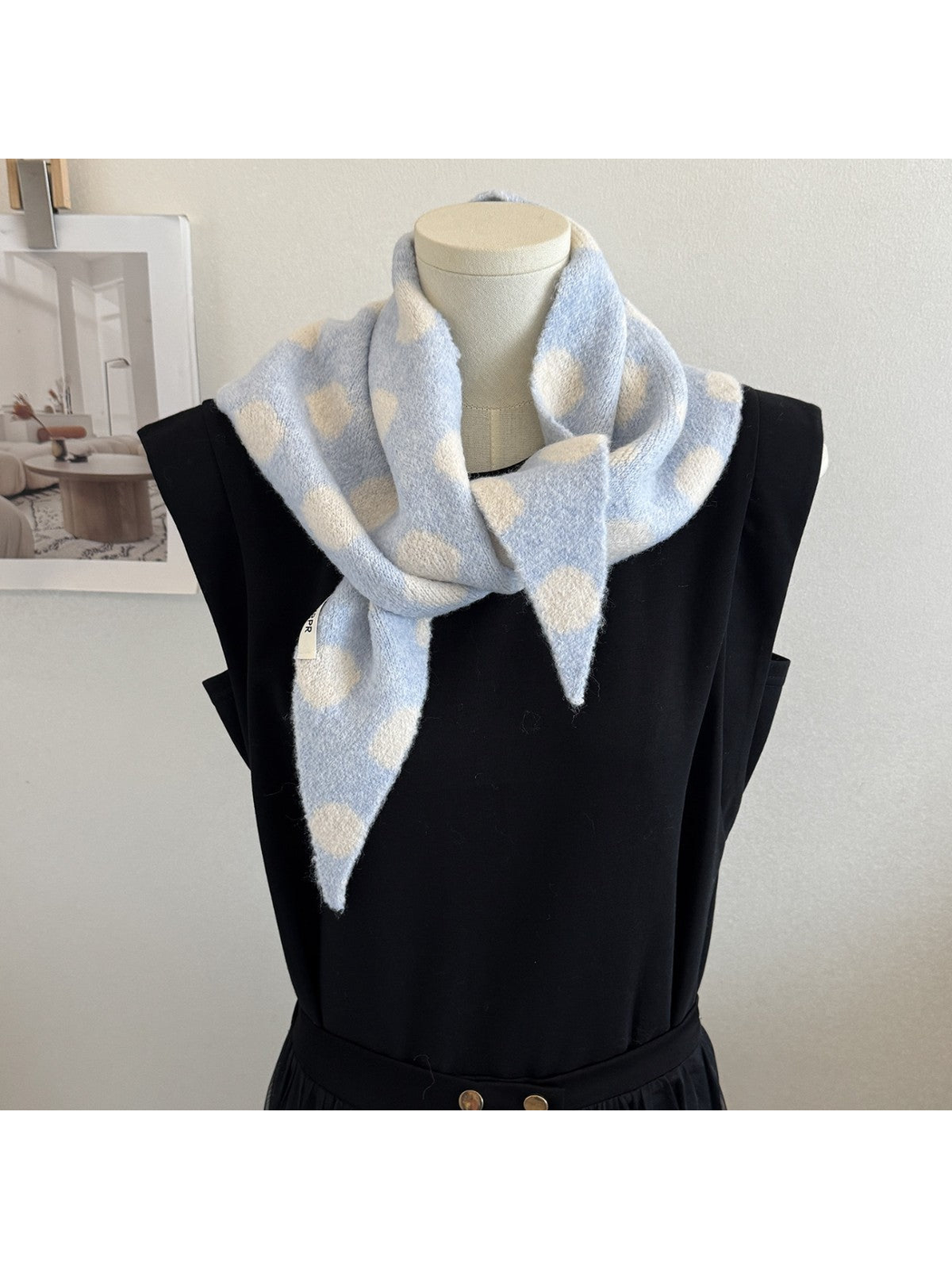 Light blue and cream polka-dot scarf draped on a black mannequin
