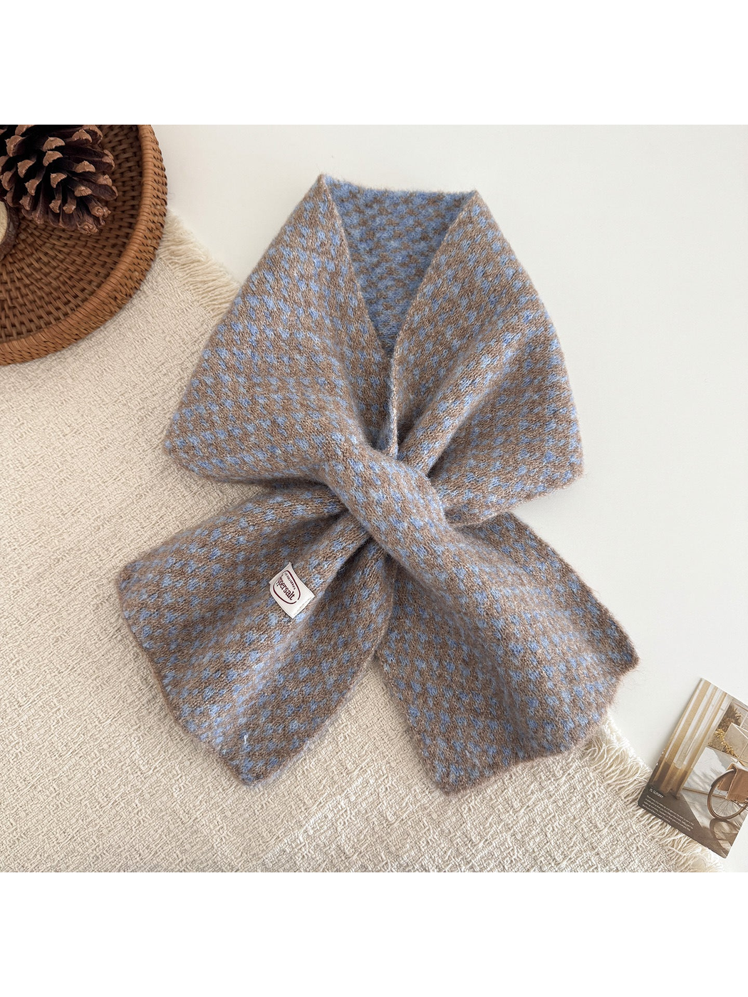 Camel and blue patterned scarf arranged in a loop on a textured surface