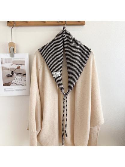 Black and white striped triangle scarf draped over a cream sweater