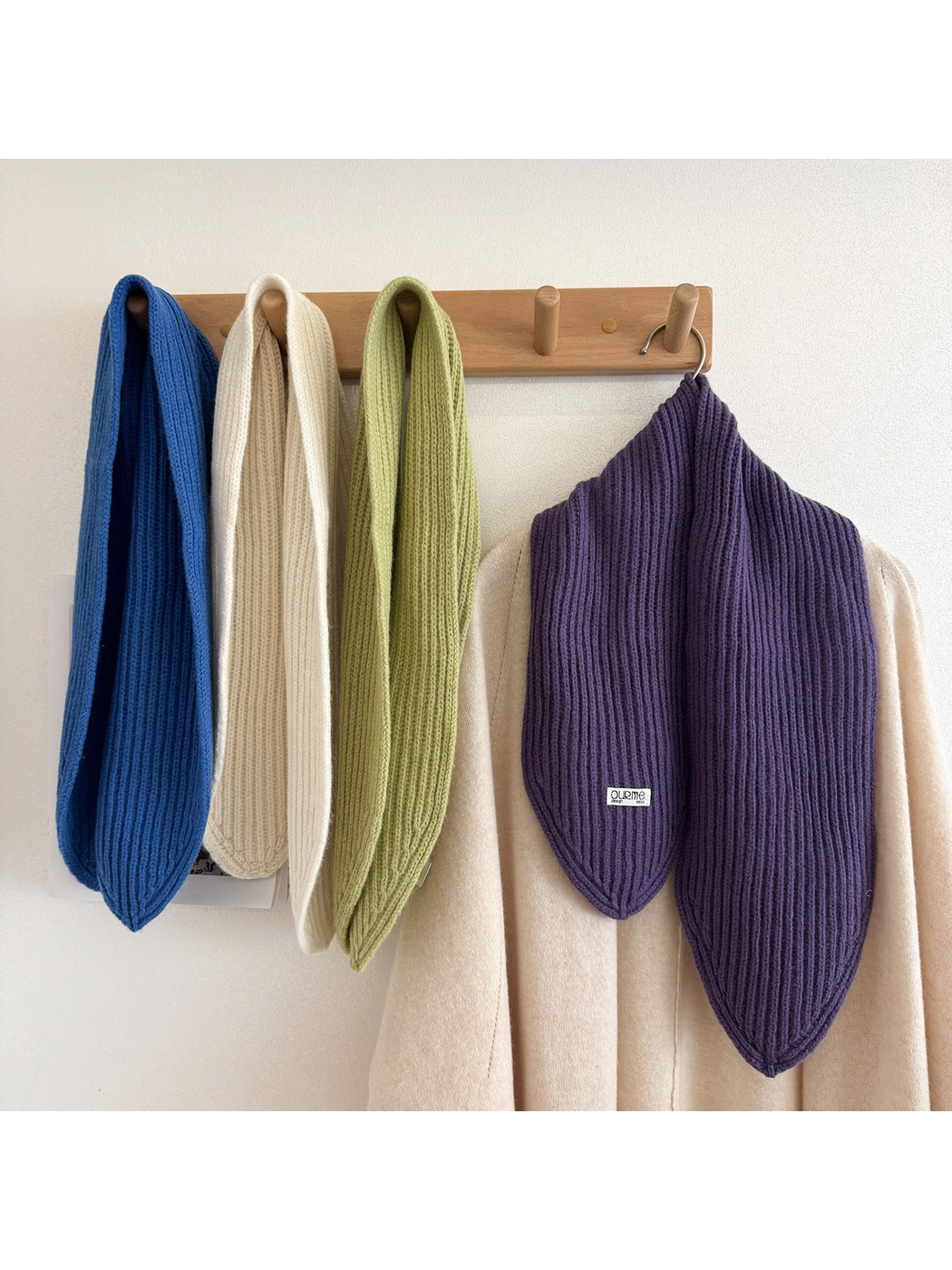 Blue, cream, green, and purple ribbed knit scarves hanging on a wall rack