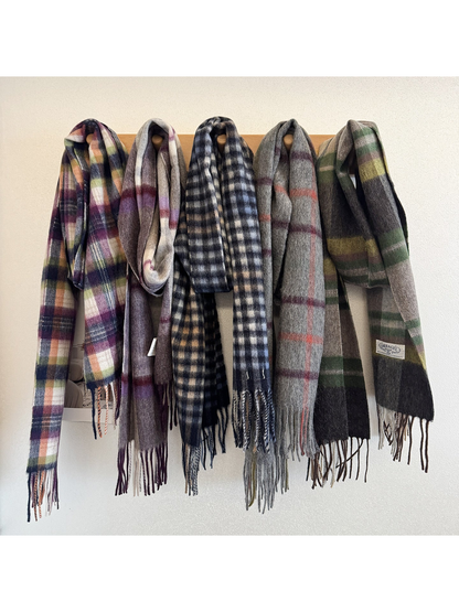 Multiple plaid scarves hanging together on wall hooks