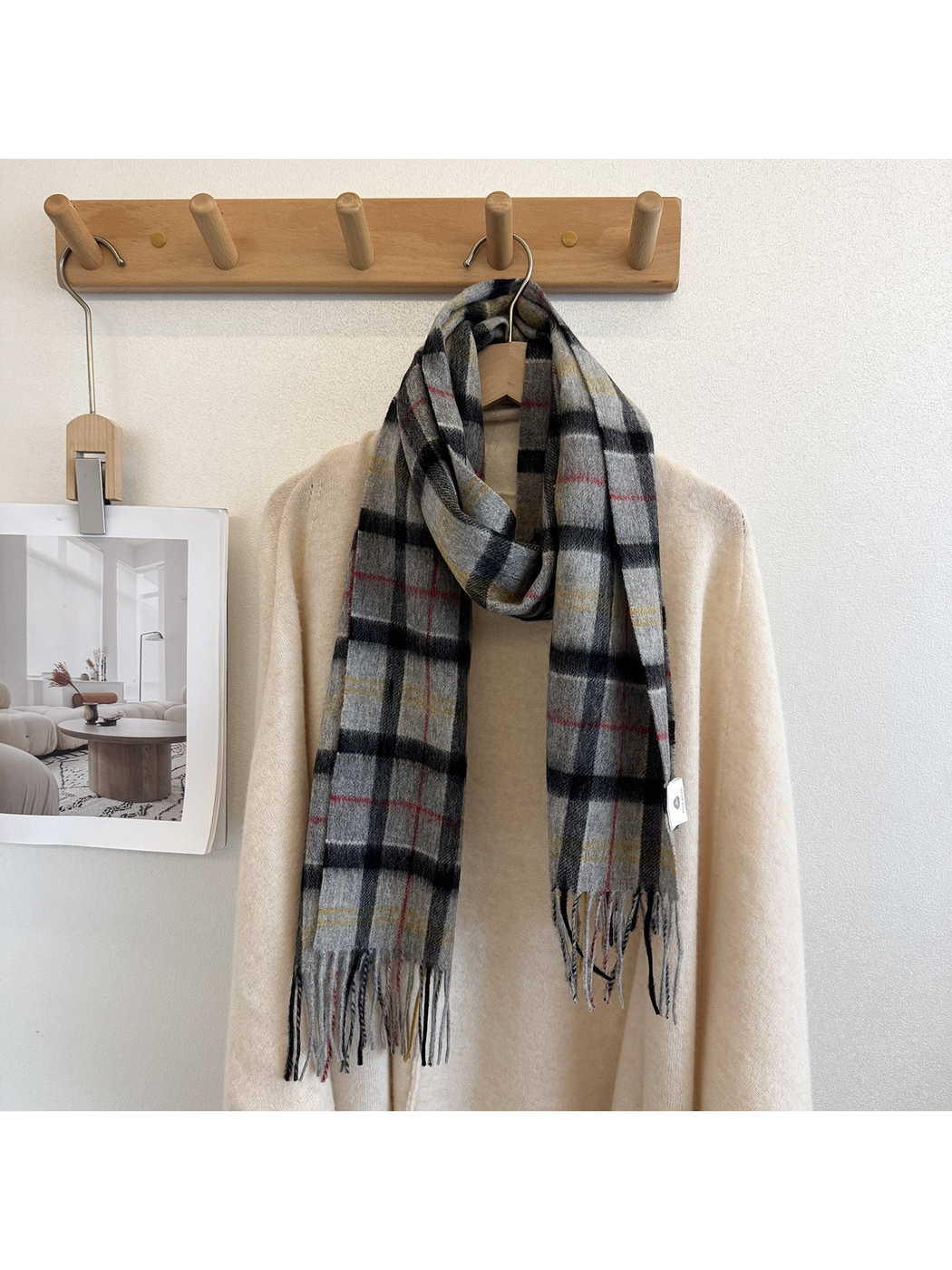 Plaid scarf draped around a cream sweater on a wall hook