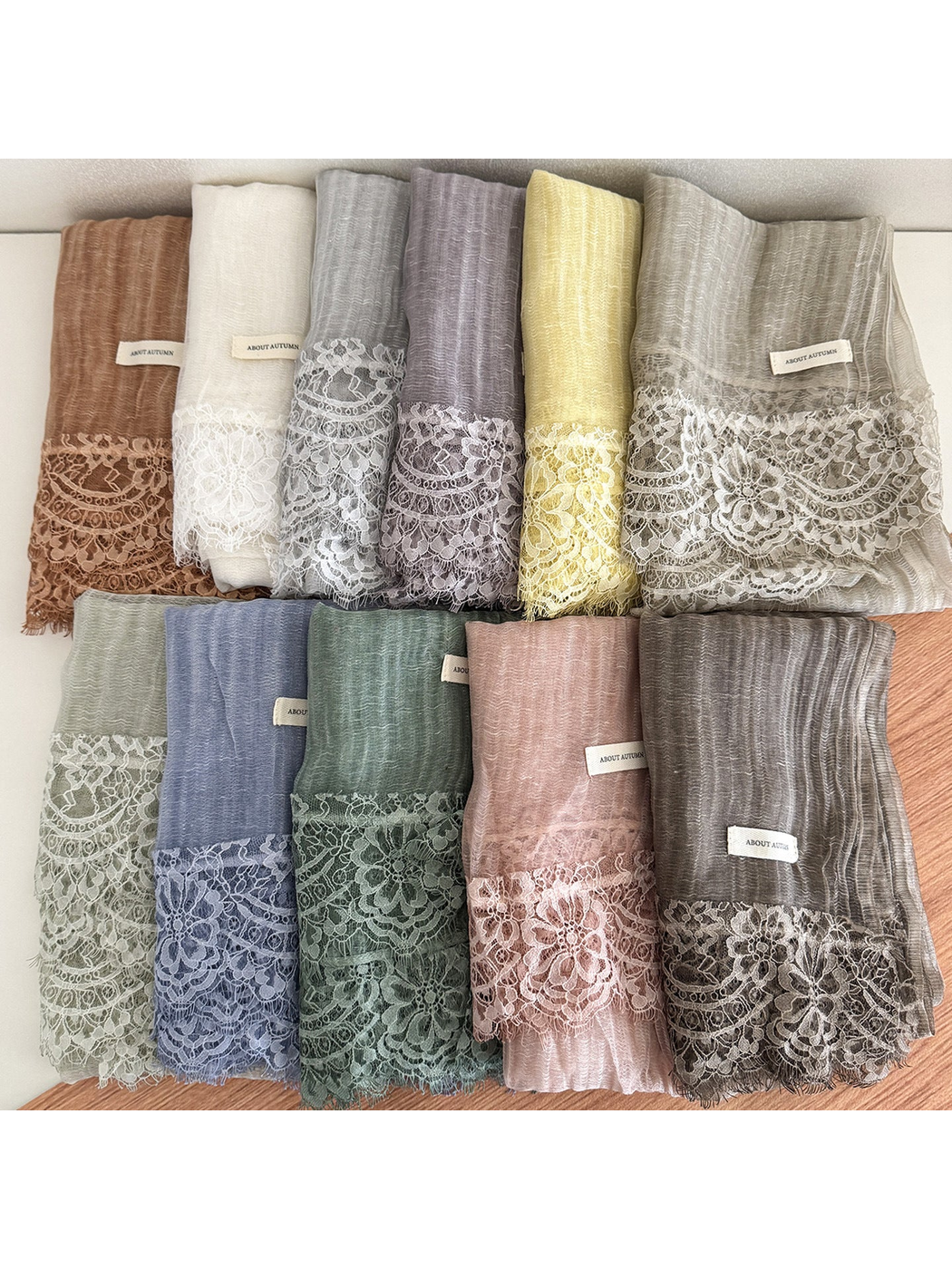 Multiple color variants of a narrow scarf with floral lace trim displayed together