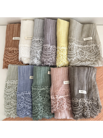 Multiple color variants of a narrow scarf with floral lace trim displayed together