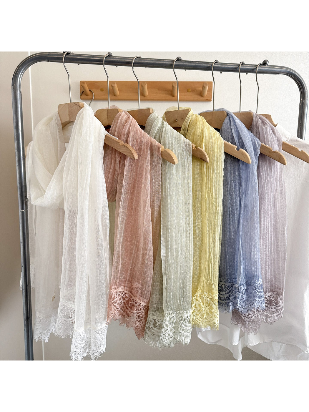 Multiple narrow scarves with lace-trimmed ends hanging on a clothing rack