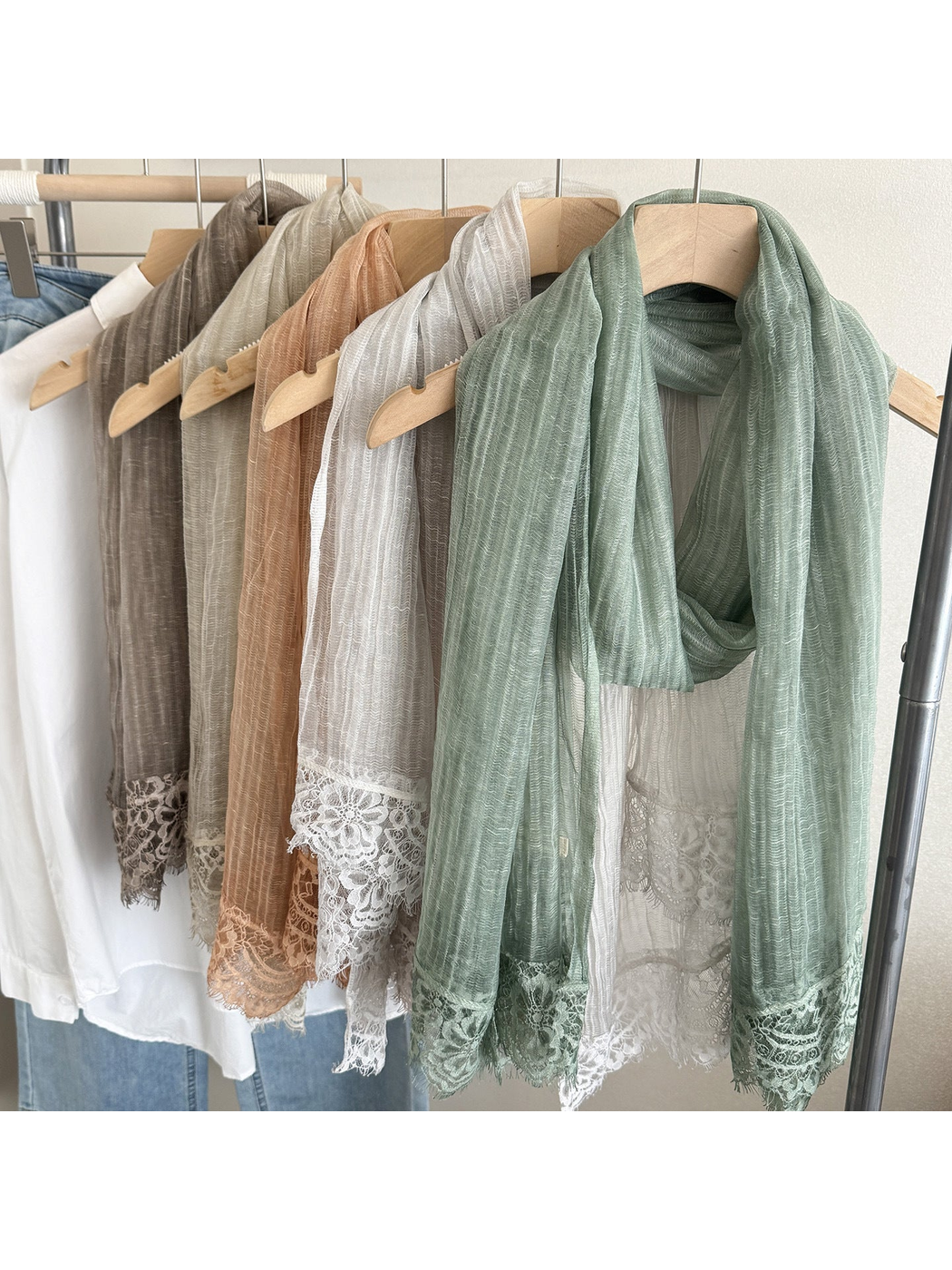 Narrow scarves in assorted colors hanging on wooden hangers