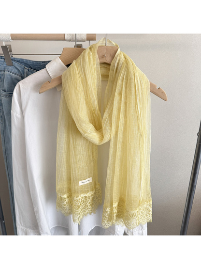 Yellow narrow scarf with floral lace trim hanging on a clothing rack