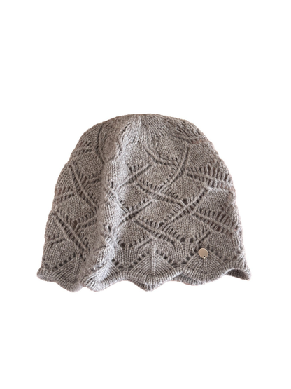 Cable-knit beanie with earflap and short visor-like brim on a white background