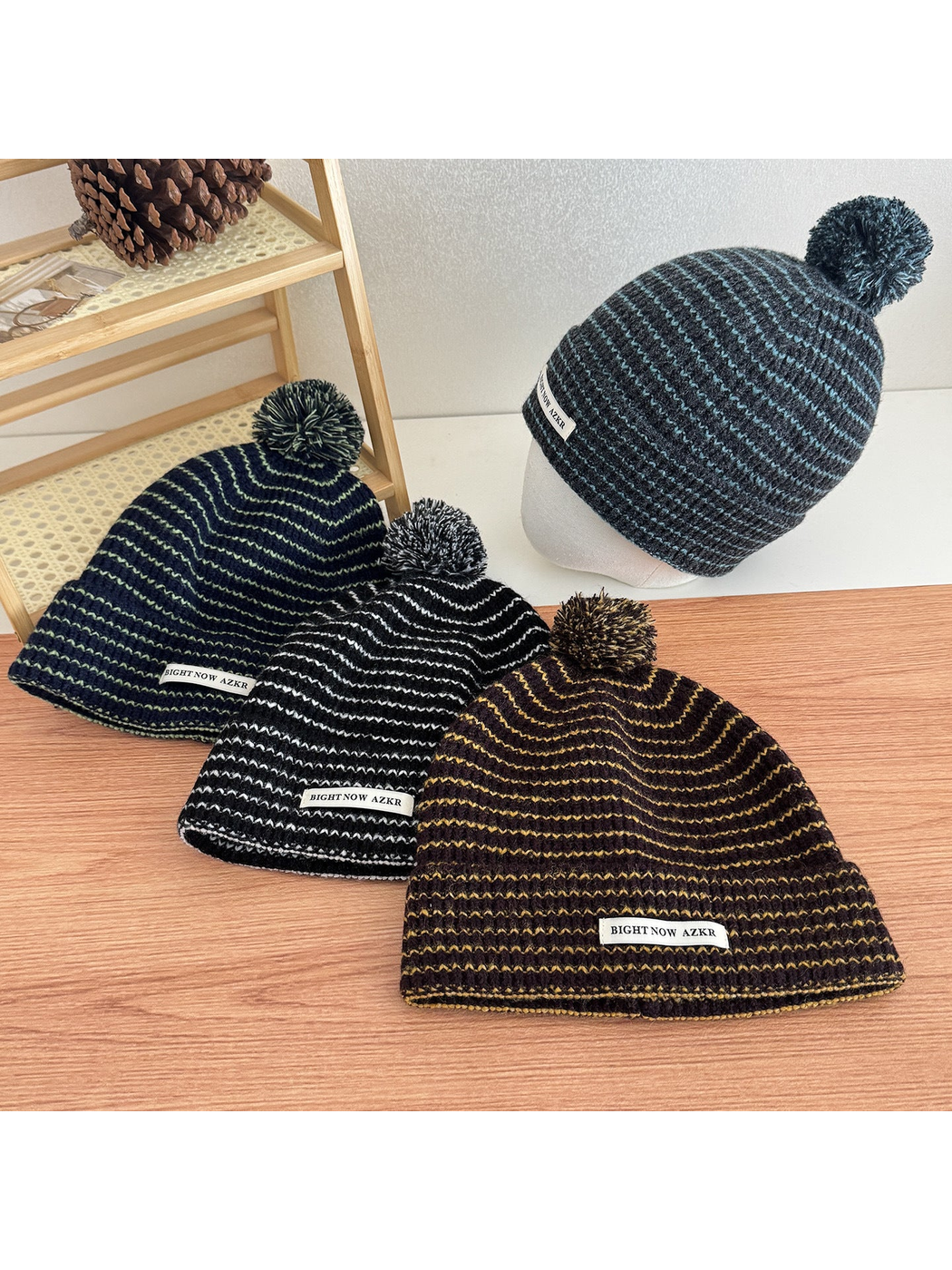 Four pom-pom beanies in different striped colorways displayed together