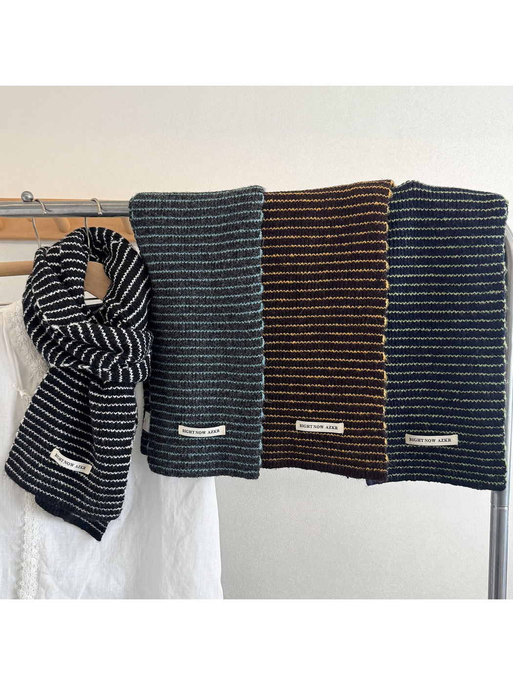Four striped knit scarves hanging together in dark brown, black, dark green, and gray blue