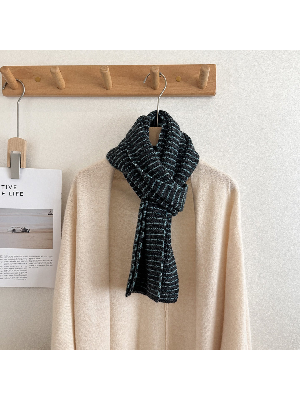 Gray-blue striped knit scarf draped on a mannequin over a cream cardigan