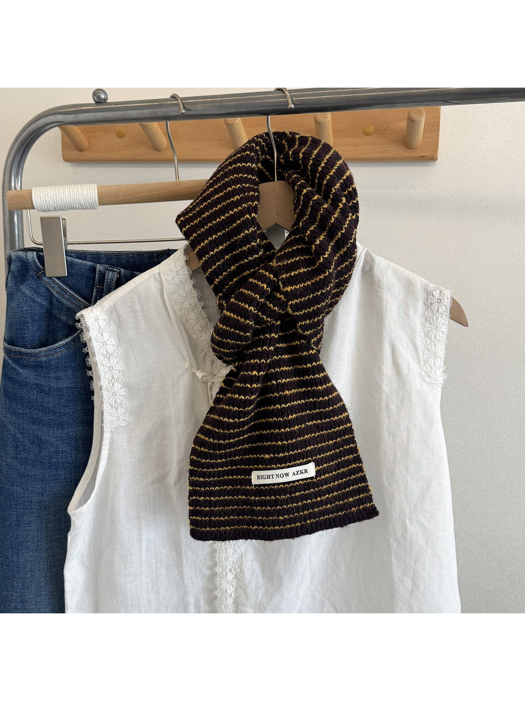 Dark brown striped knit scarf draped on a mannequin over a white blouse