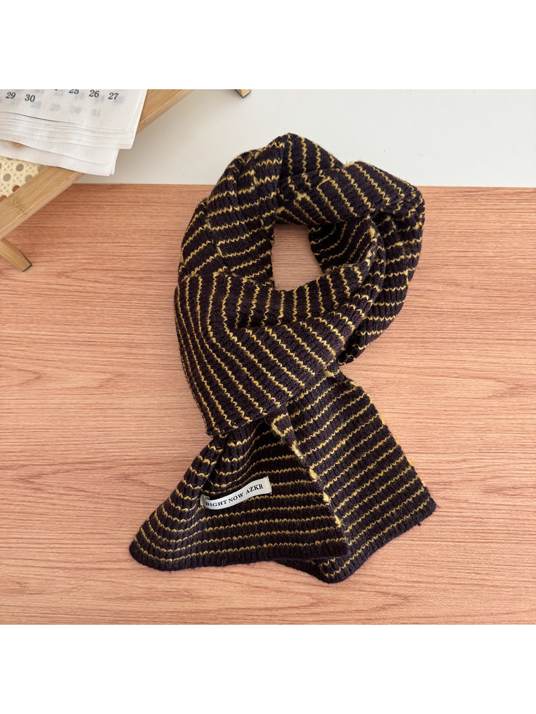 Dark Brown striped knit scarf looped on a tabletop