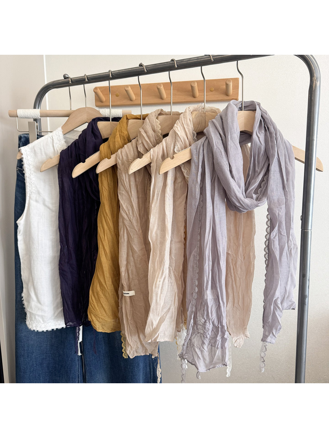 Multiple scarves in light and dark colors hanging on a clothing rack