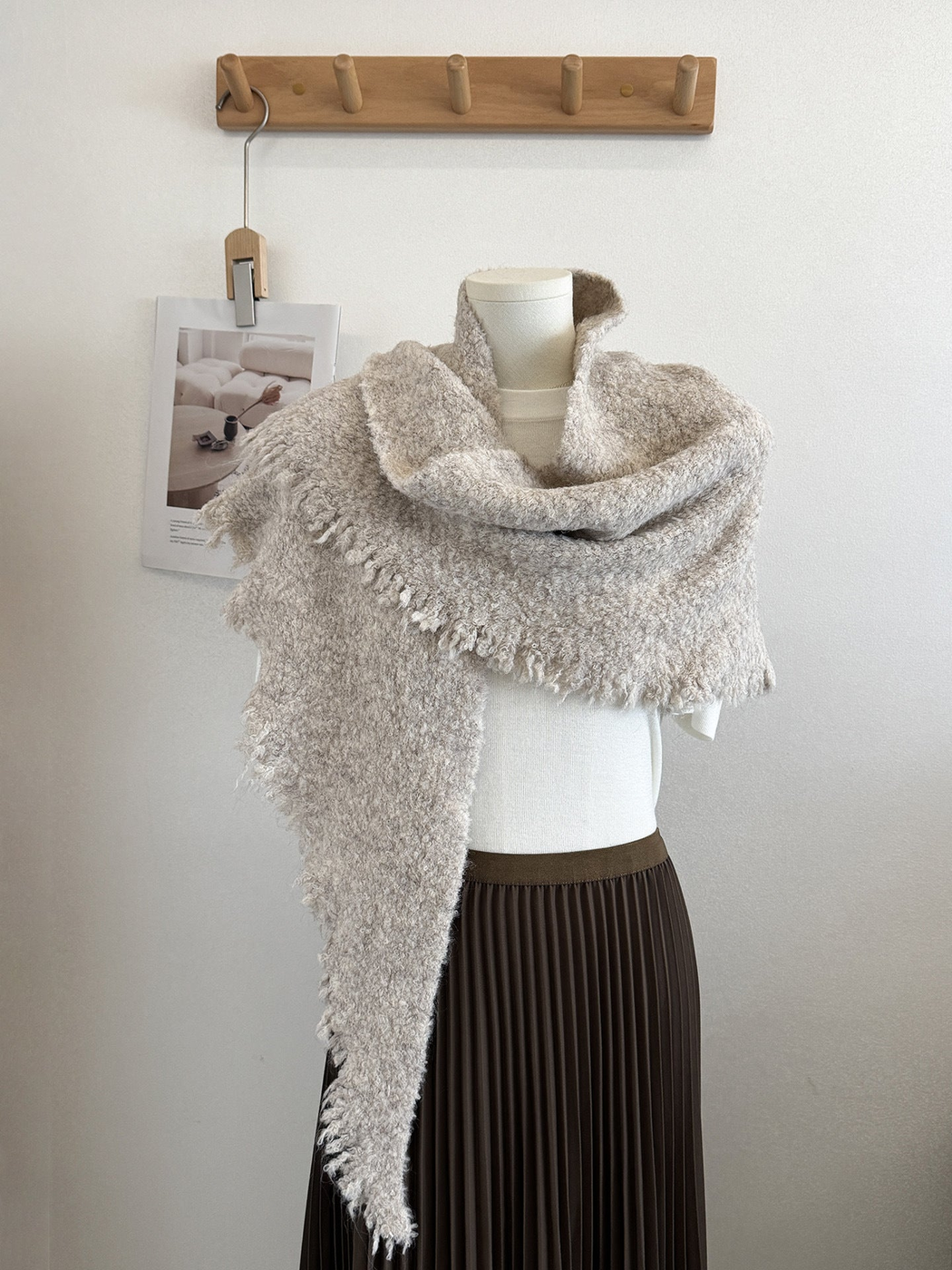Beige textured scarf with fringed edges draped on a mannequin