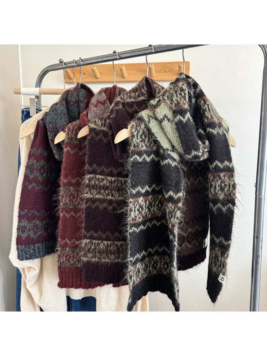 Multiple dark-toned patterned scarves displayed on a clothing rack