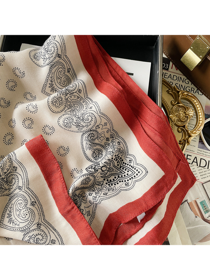 Close-up of a cream paisley square scarf with a contrasting red border