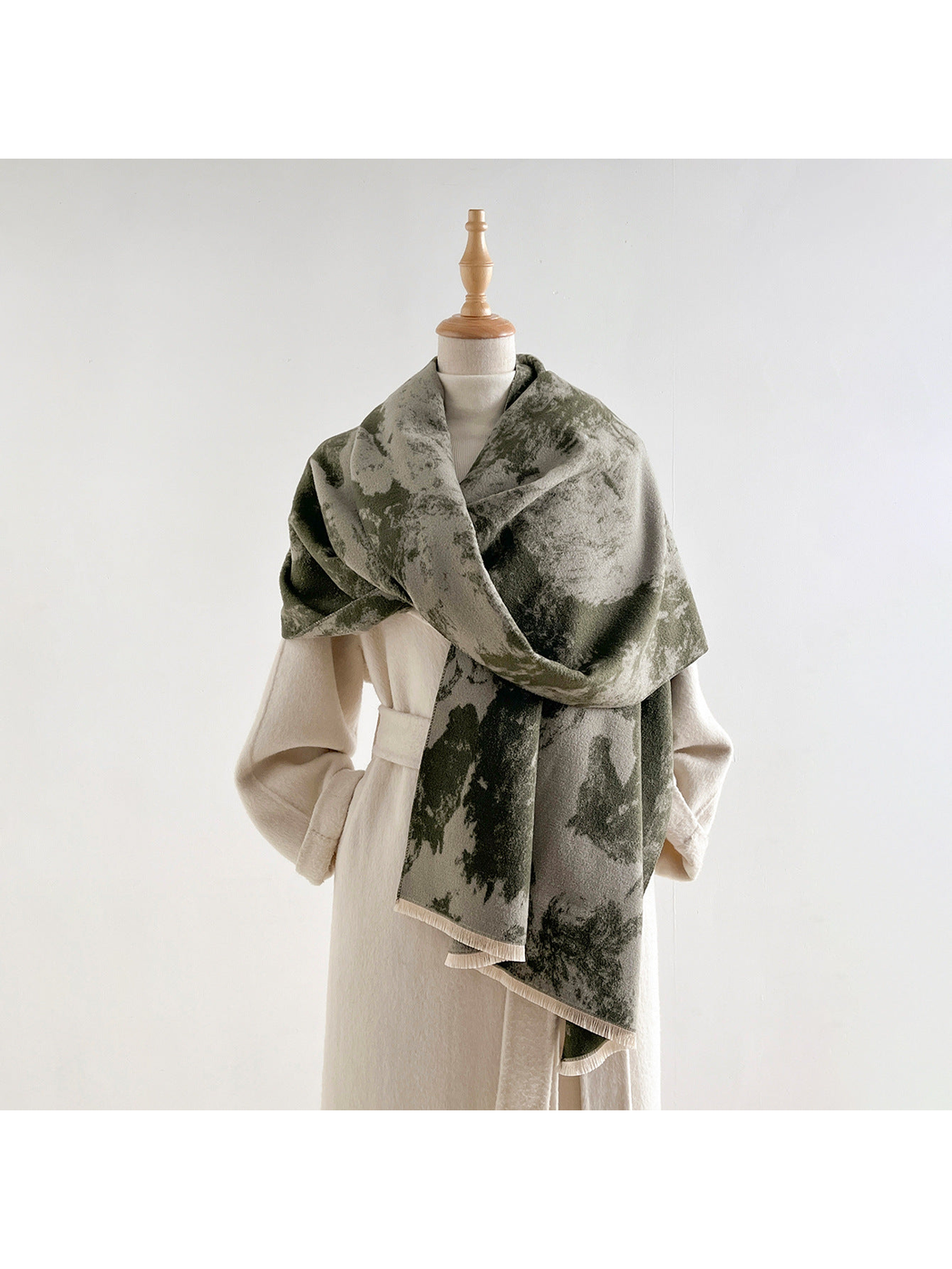 Abstract patterned scarf draped around a mannequin wearing a light coat